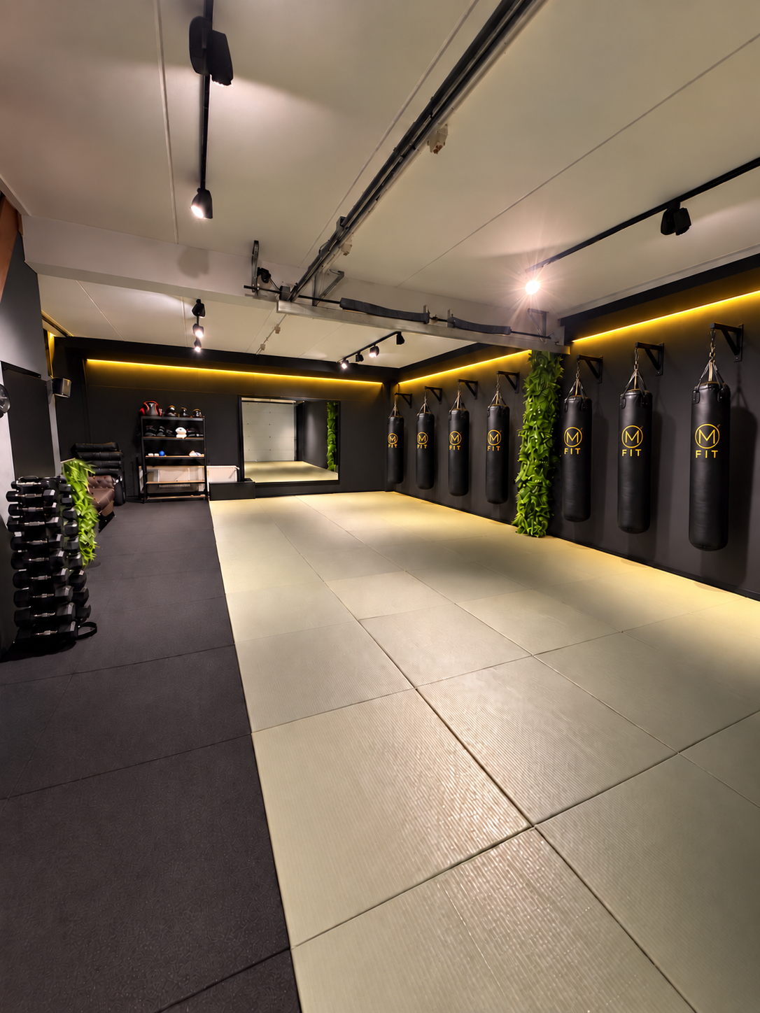 De M Fit-dojo met goudkleurige verlichting en bokszakken